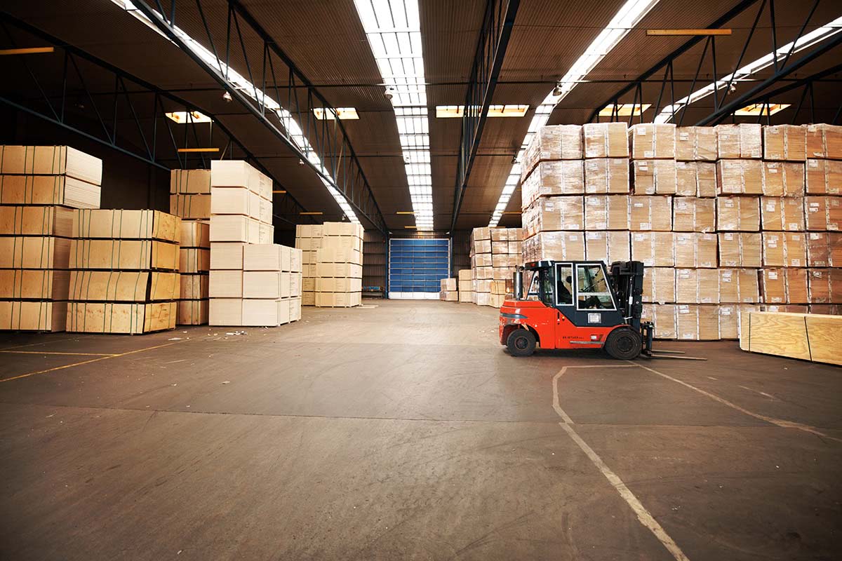 A large warehouse storing big boxes with a forklift.